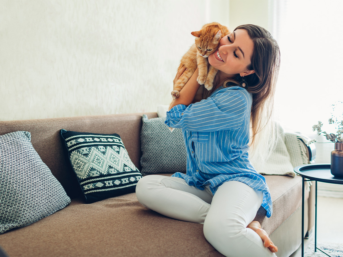 woman cuddling cat in a sunny apartment